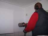 Man boort gaten in de muur met apparatuur.