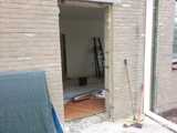 Deuropening in aanbouw met zichtbare houten of betonnen constructie.